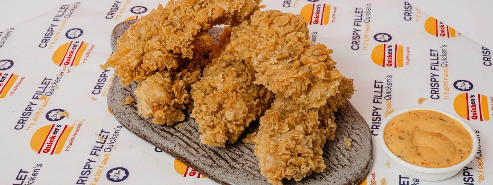 Crispy chicken strips with a dipping sauce on Quicken’s branded paper