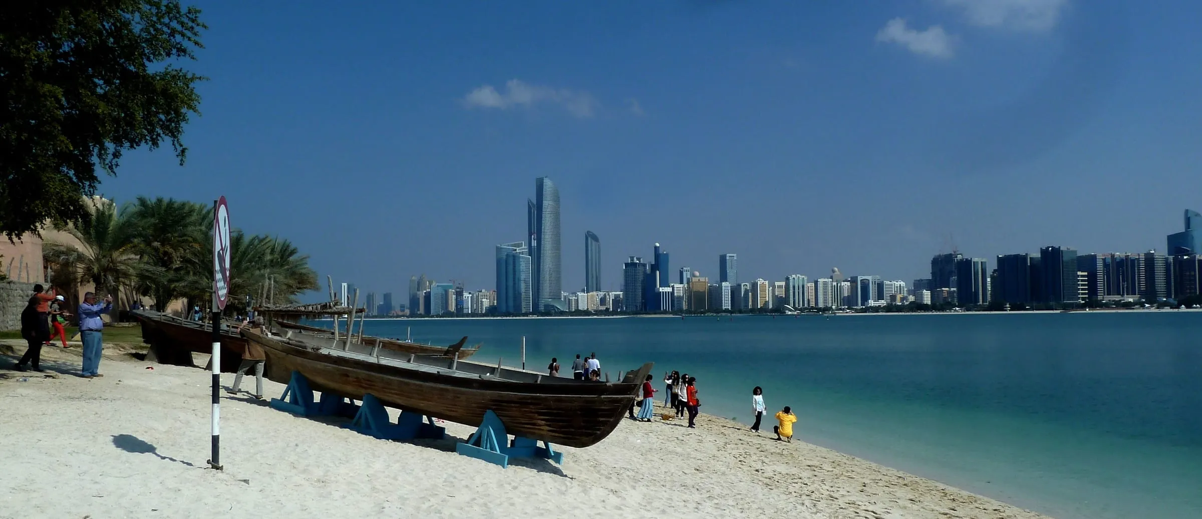 A traditional dhow on the beach at the Abu Dhabi Corniche, with the city skyline behind